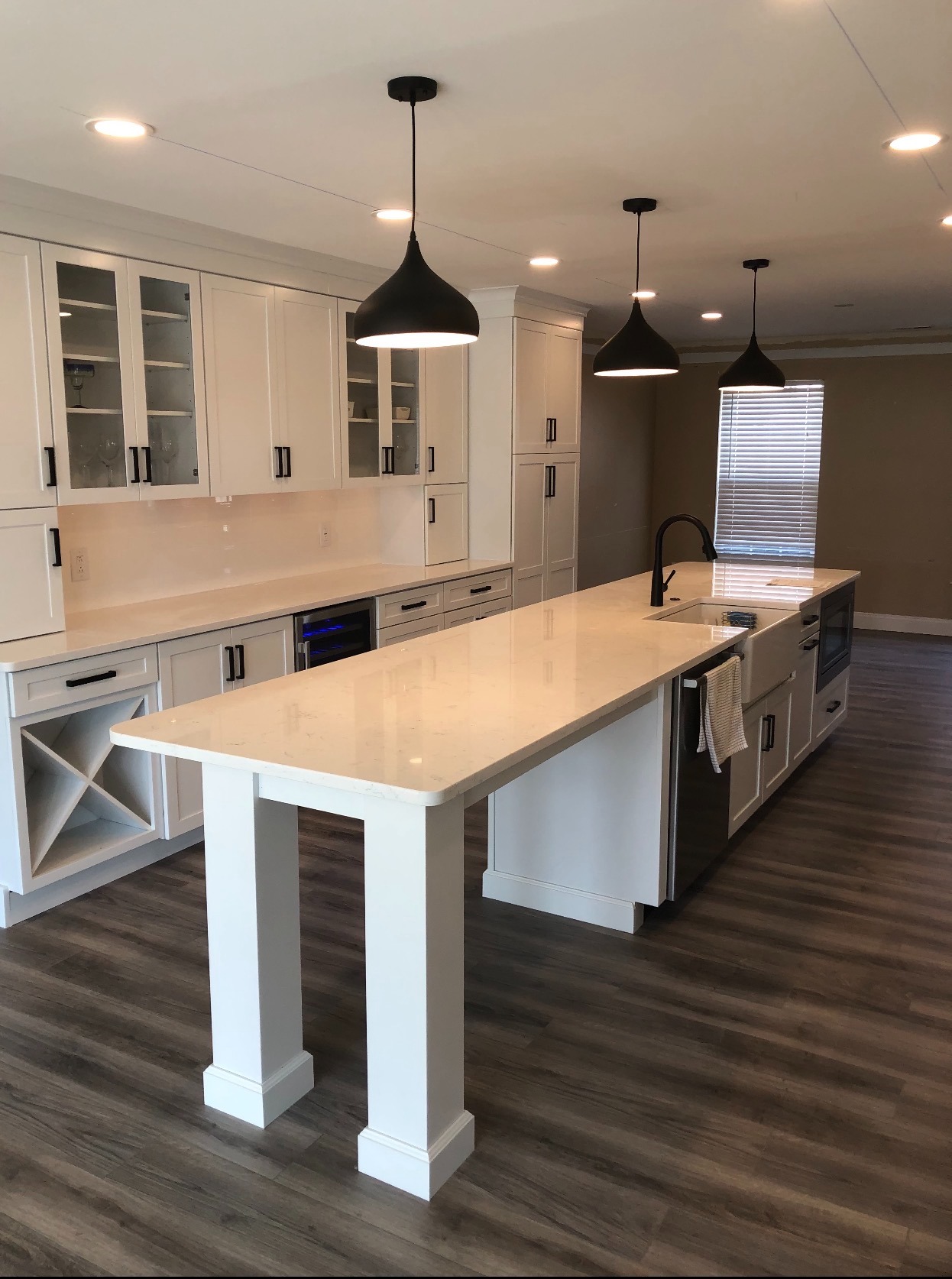 Tall white shaker kitchen with an oversized island, matte black hardware, and glass-front display cabinets