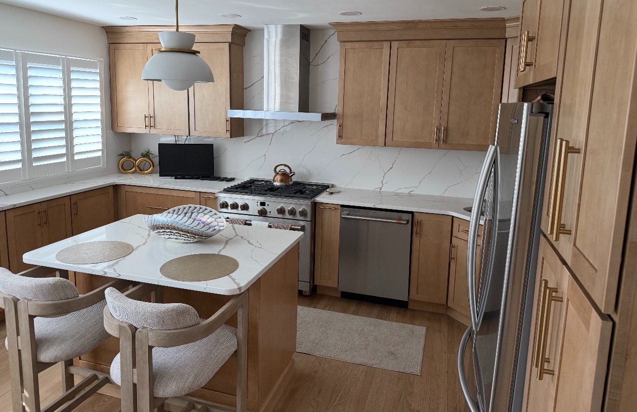 Natural oak kitchen cabinets with a full-height marble-veined quartz backsplash and island seating